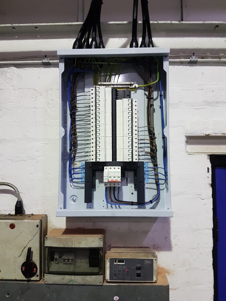 Completed industrial electrical installation with distribution board and cable containment for a factory tool room relocation.