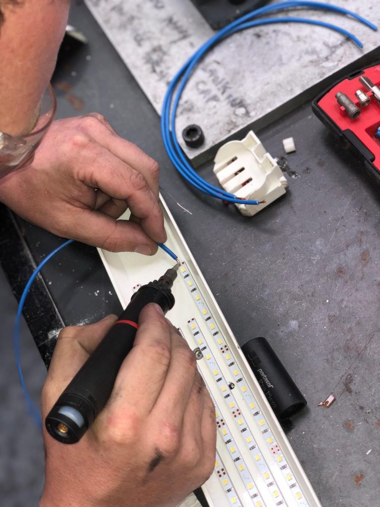 Soldering electrical connections for an industrial LED lighting upgrade.