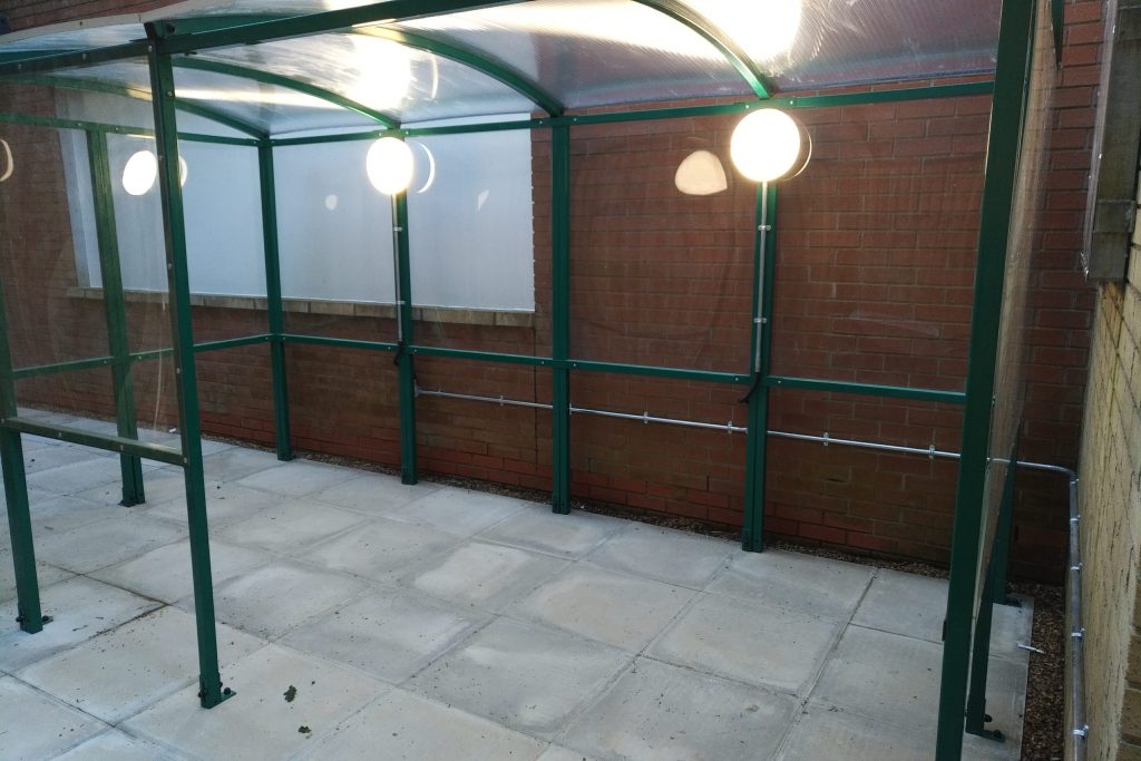 Commercial smoking shelter illuminated by new LED external lighting installation.
